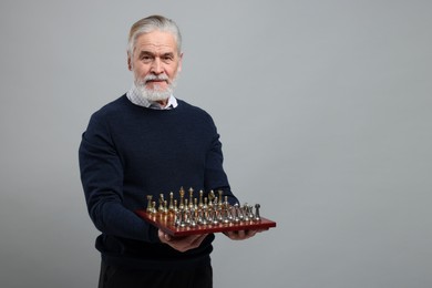 Photo of Man with chessboard and game pieces on light gray background, space for text