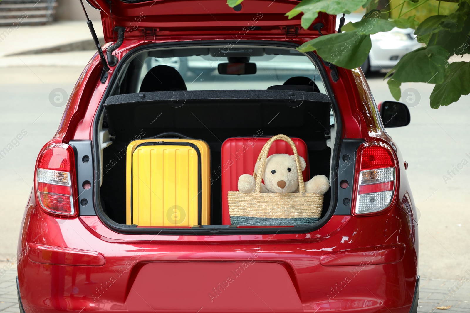 Photo of Suitcases and teddy bear in car trunk outdoors, closeup