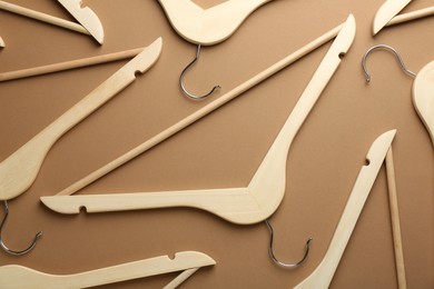 Photo of Wooden hangers on brown background, flat lay