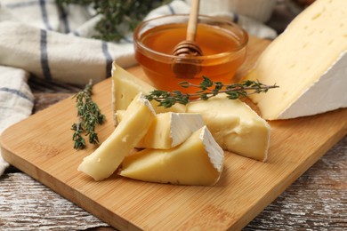 Photo of Tasty Camembert cheese with thyme and honey on wooden table