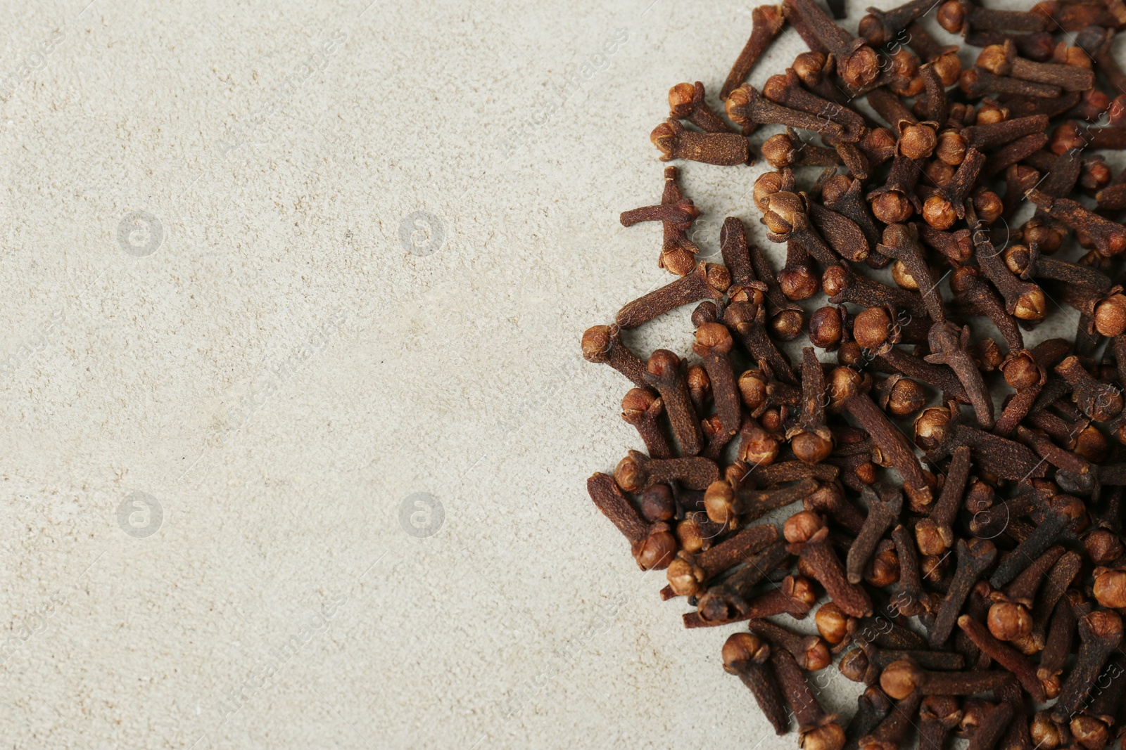 Photo of Pile of aromatic dry cloves on white table, flat lay. Space for text