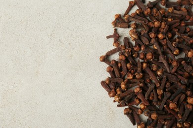 Photo of Pile of aromatic dry cloves on white table, flat lay. Space for text