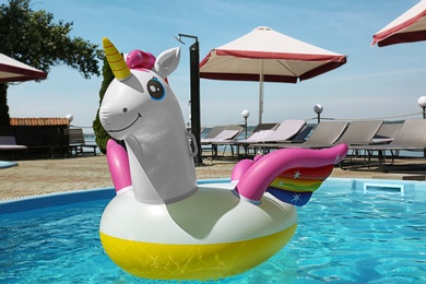 Funny inflatable unicorn ring floating in swimming pool on sunny day, outdoors