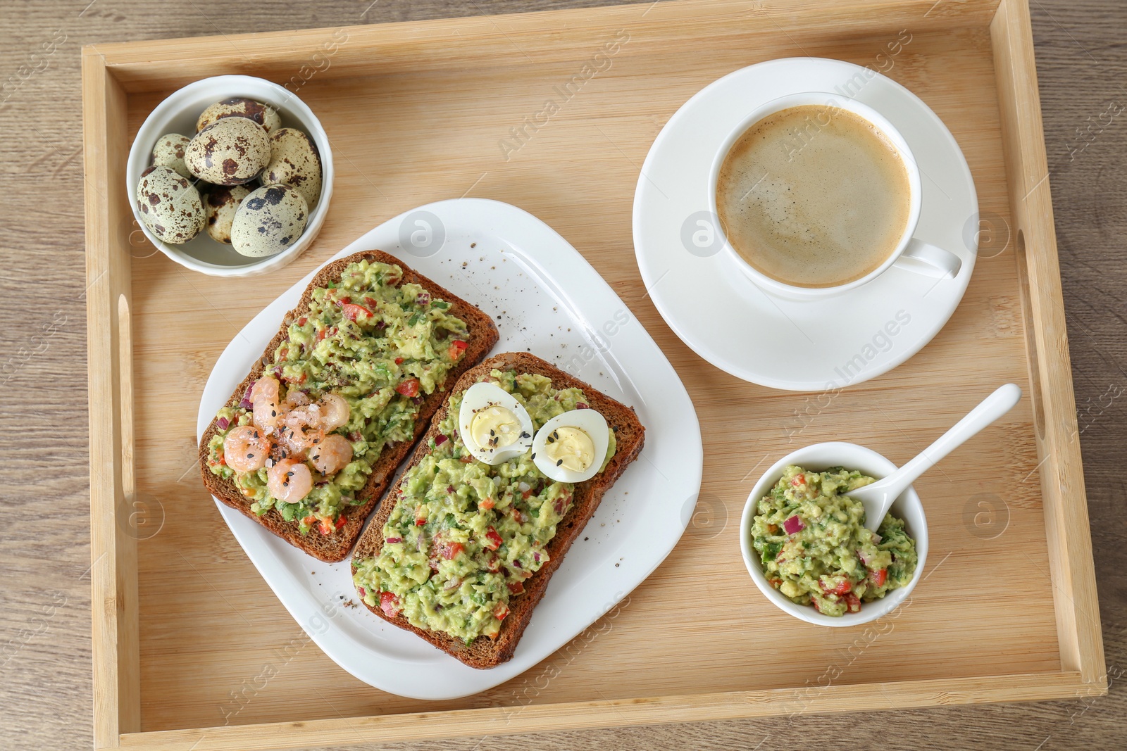 Photo of Slices of bread with tasty guacamole, eggs, shrimp and coffee on wooden table, top view