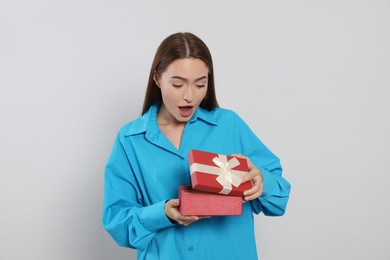 Photo of Portrait of emotional young woman opening gift box on grey background