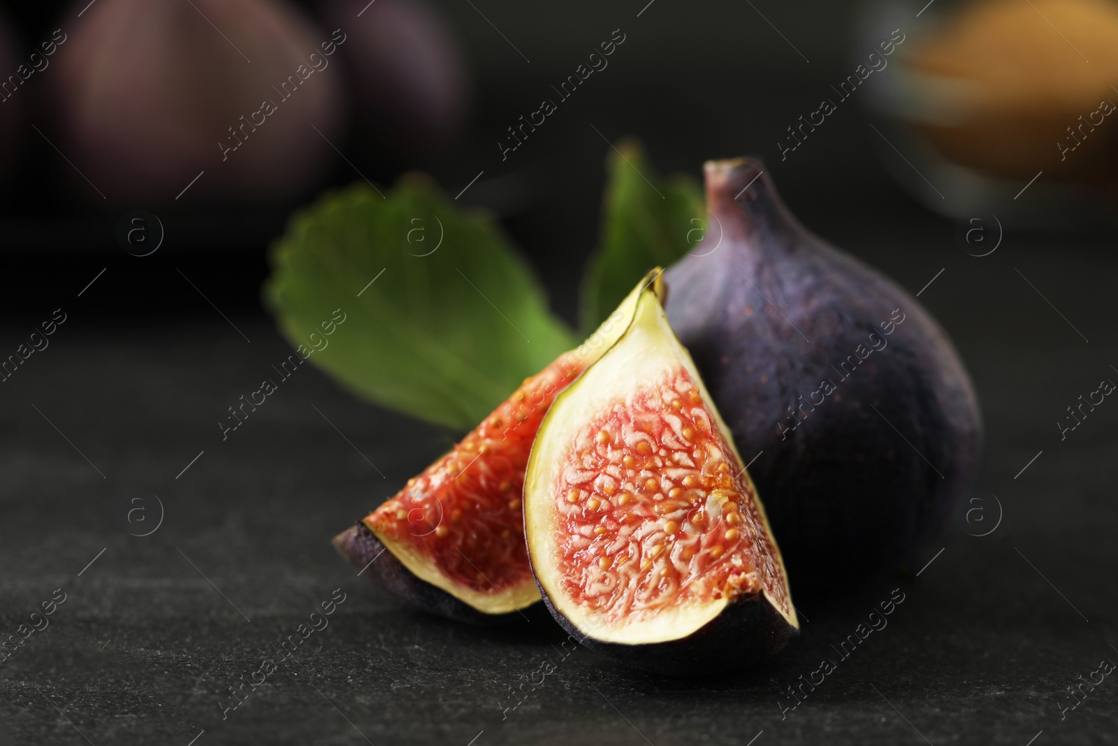 Photo of Tasty raw figs on black slate table, closeup