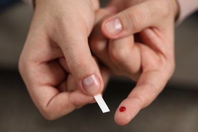 Diabetes test. Man checking blood sugar level with glucometer on blurred background, closeup