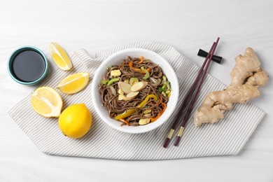 Photo of Stir-fry. Delicious cooked noodles with chicken and vegetables in bowl served on light wooden table, flat lay