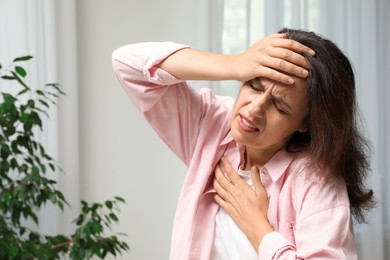 Photo of Mature woman suffering from breathing problem indoors