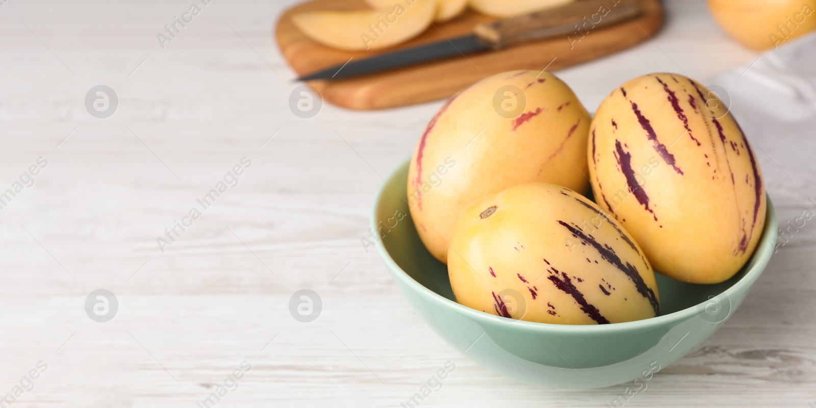 Image of Fresh ripe pepino melons in bowl on white wooden table, space for text. Banner design