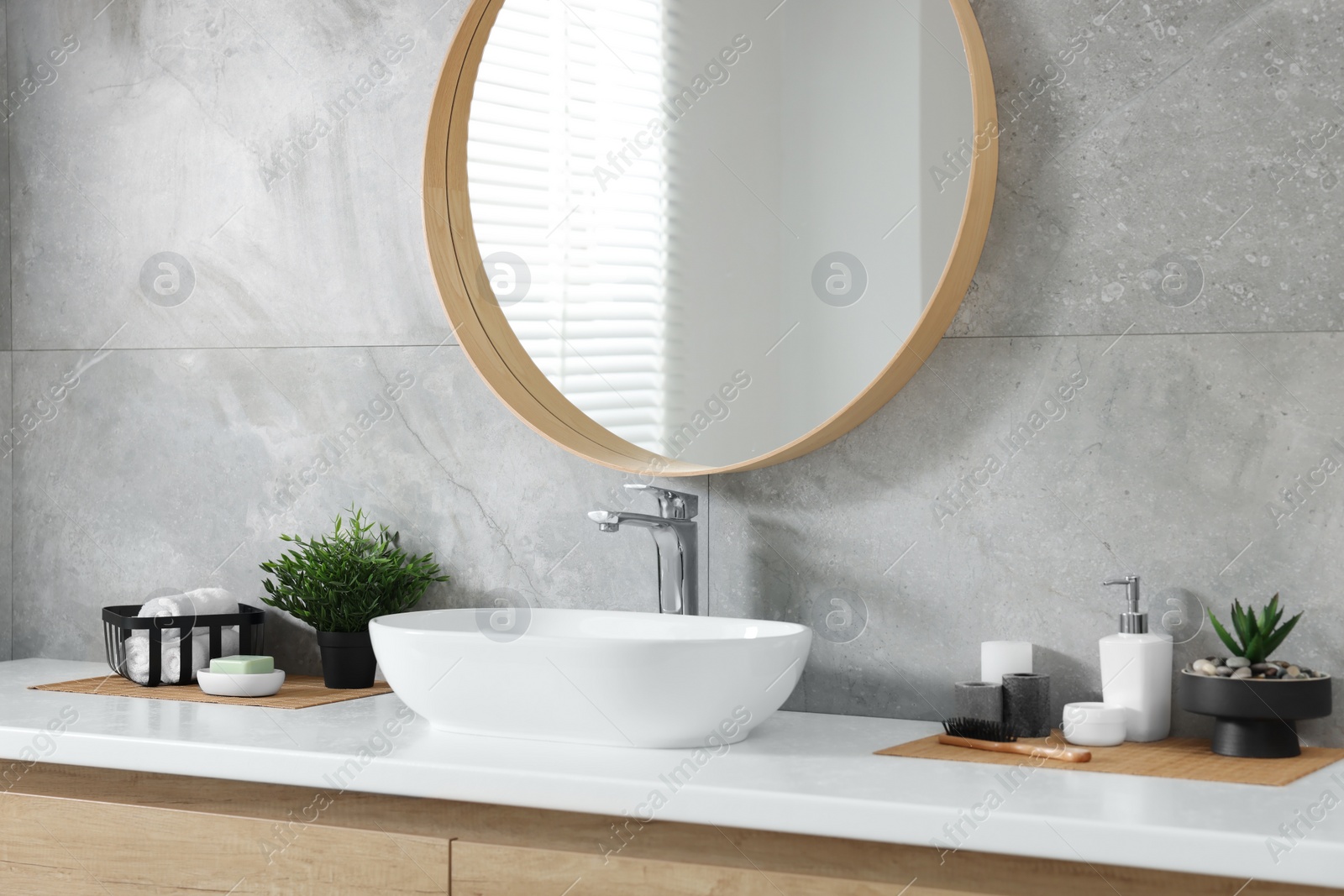 Photo of Potted artificial plants, rolled towels and toiletries near sink on bathroom vanity