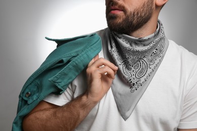 Photo of Fashionable young man in stylish outfit with bandana on grey background, closeup