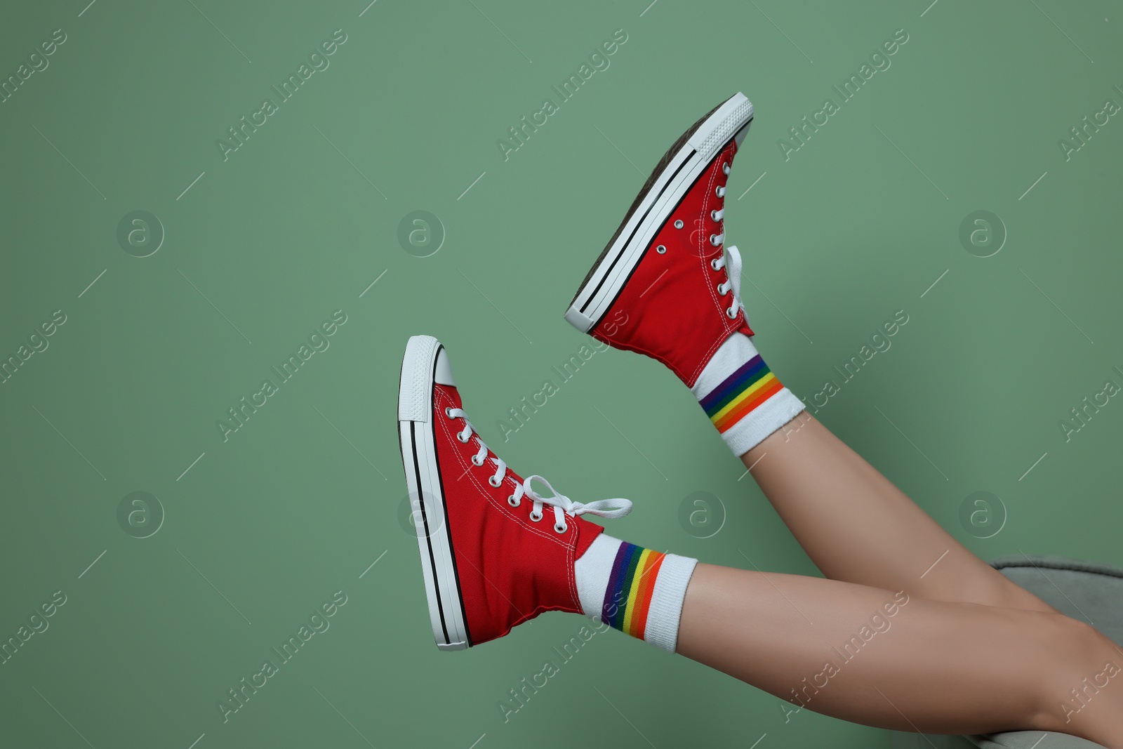 Photo of Woman in stylish gumshoes on pale green background, closeup. Space for text