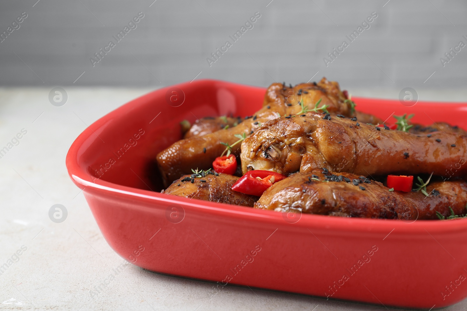 Photo of Chicken legs glazed with soy sauce, black sesame, chili pepper and thyme on light table, closeup. Space for text