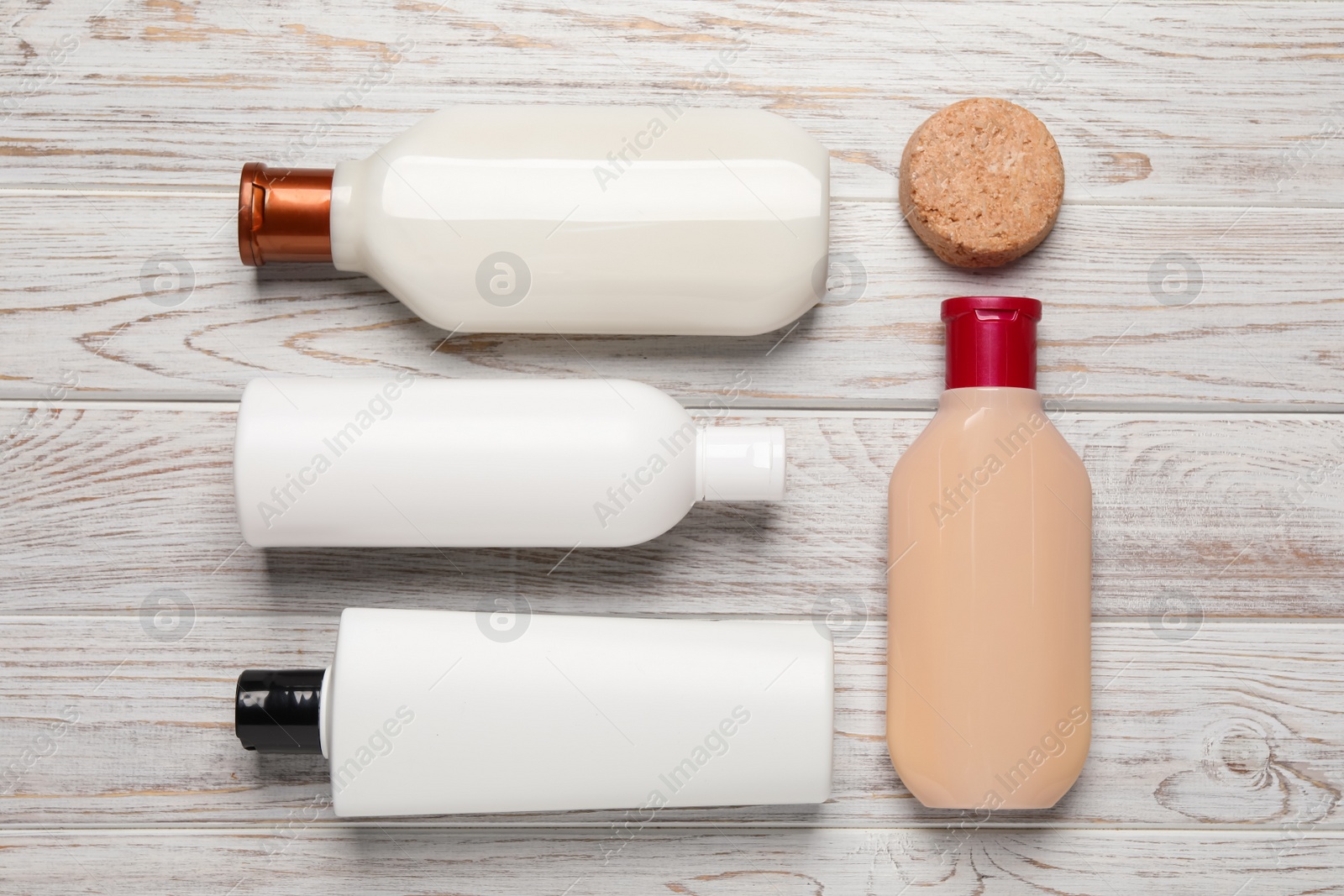Photo of Shampoo bottles and solid shampoo bar on white wooden table, flat lay