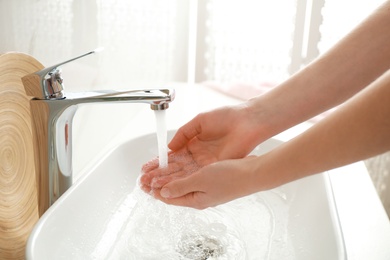 Photo of Woman washing hands indoors, closeup. Bathroom interior