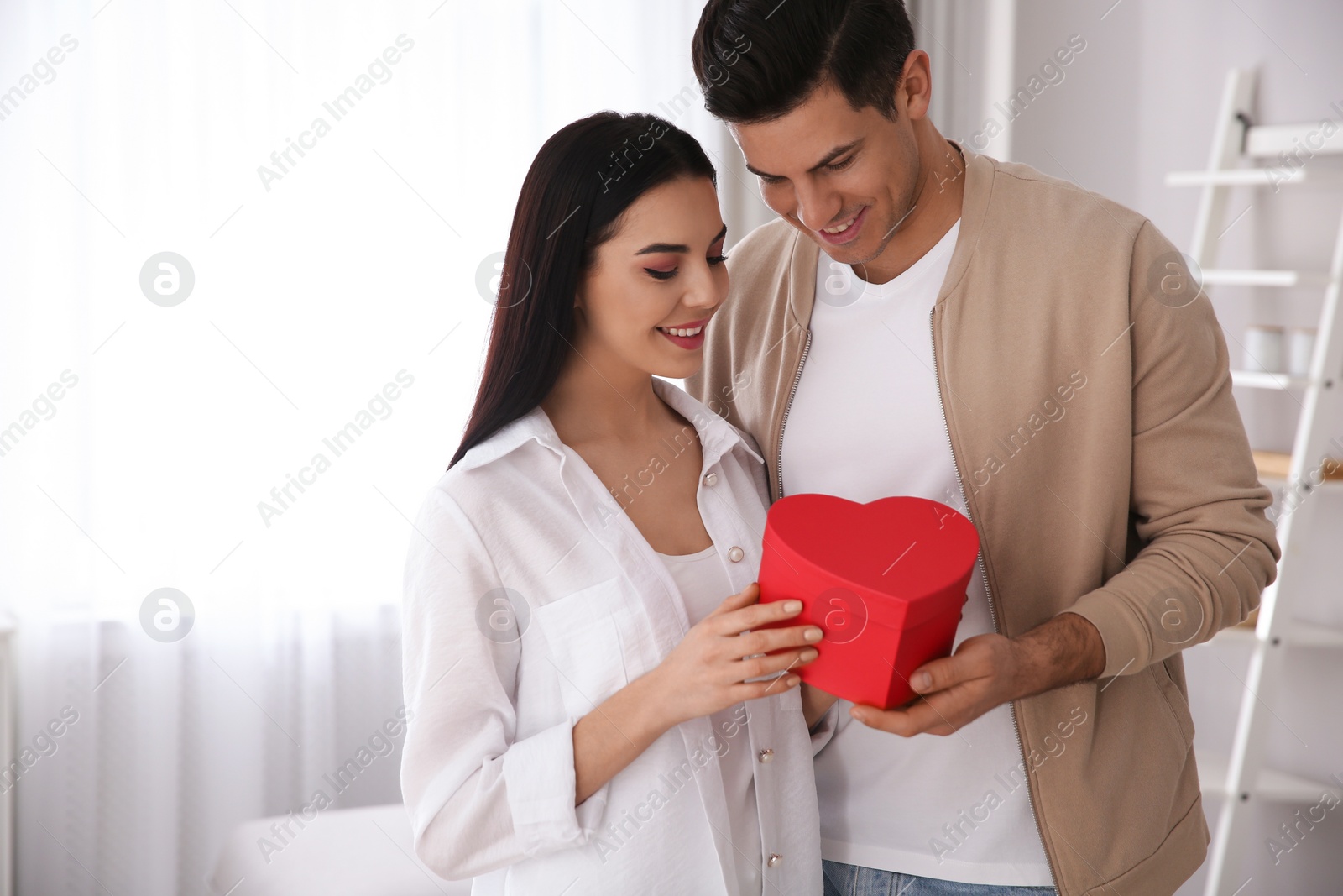 Photo of Lovely couple with gift box at home. Valentine's day celebration