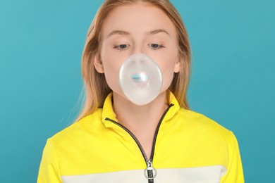 Photo of Beautiful young woman blowing bubble gum on light blue background