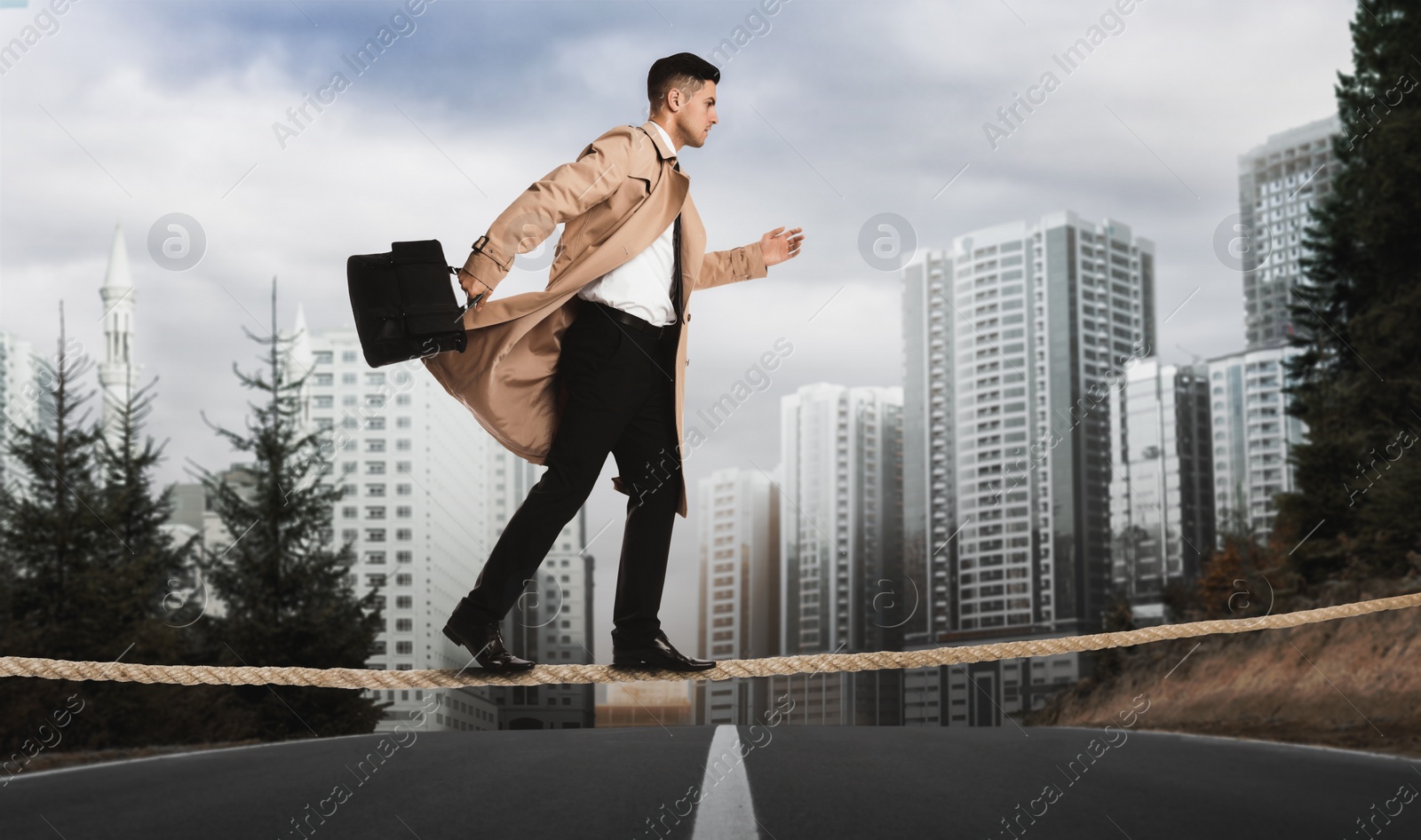 Image of Risks and challenges of entrepreneurship. Concentrated businessman with portfolio crossing road on rope outdoors