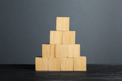 Photo of Pyramid of blank cubes on dark wooden table