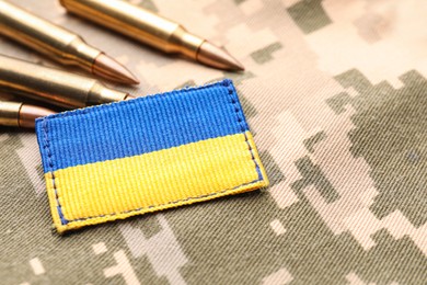 Photo of Military patch and bullets on pixel Ukrainian camouflage, closeup