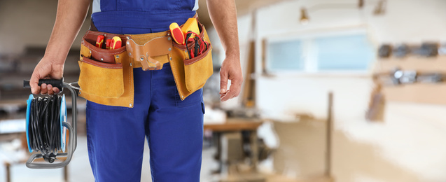 Closeup view of electrician with tools indoors, space for text. Banner design