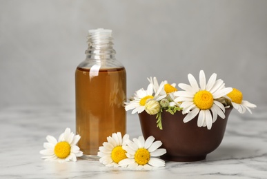 Composition with bottle of chamomile essential oil on table