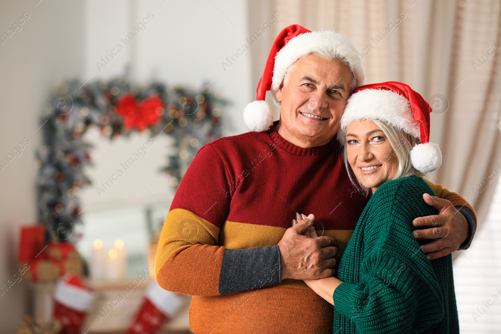 Photo of Happy mature couple in Santa hats at home. Christmas celebration