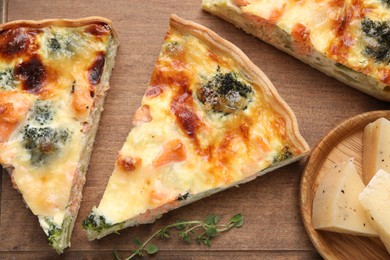 Photo of Pieces of delicious homemade quiche and ingredients on wooden table, flat lay