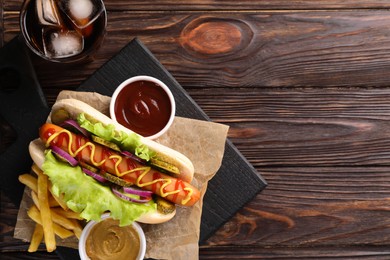 Delicious hot dog with lettuce, onion and pickle served on wooden table, top view. Space for text