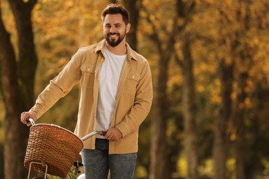 Young man with bicycle in autumn park, space for text