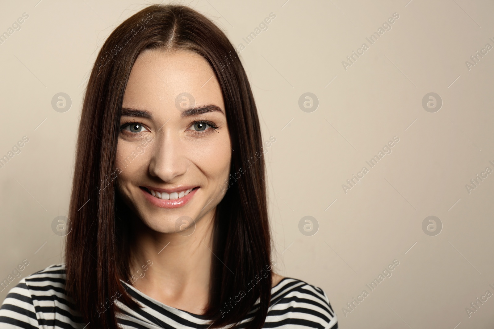 Photo of Portrait of pretty young woman with gorgeous chestnut hair and charming smile on light background, space for text