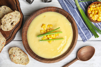 Delicious corn cream soup served on white wooden table, flat lay