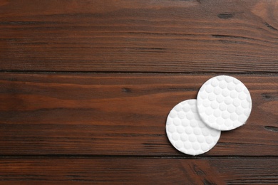 Photo of Cotton pads on wooden background, top view. Space for text