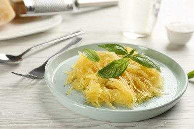 Photo of Tasty spaghetti squash with basil and cheese served on white wooden table, closeup