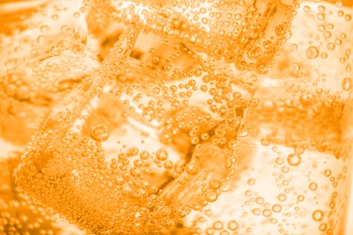 Image of Closeup view of soda water with ice. Toned in orange