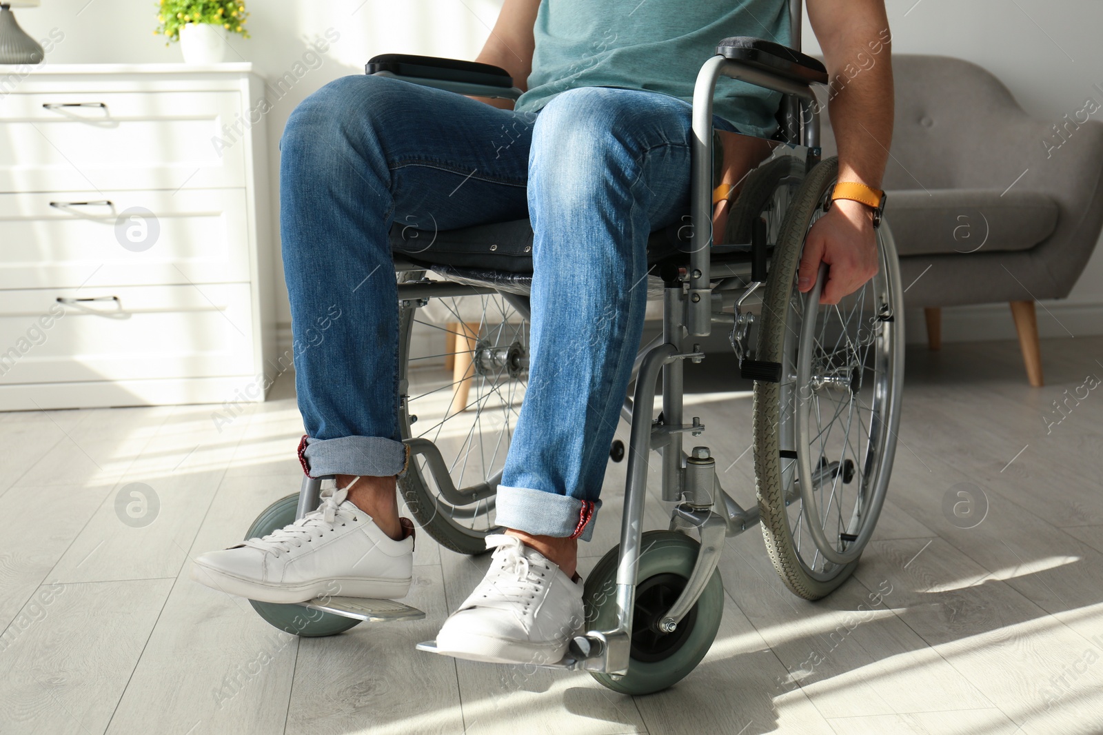 Photo of Young man sitting in wheelchair indoors, closeup