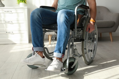 Young man sitting in wheelchair indoors, closeup