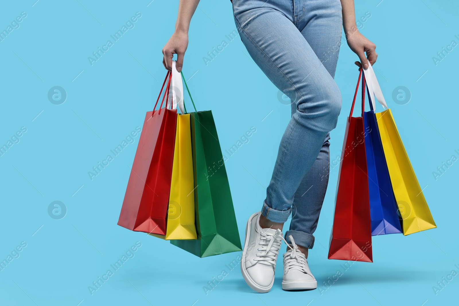 Photo of Woman with shopping bags on light blue background, closeup. Space for text