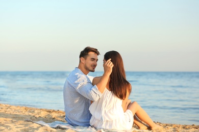 Happy young couple sitting together on beach