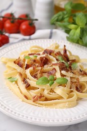 Photo of Tasty pasta with bacon and basil on white table, closeup