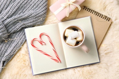 Flat lay composition with cup of hot winter drink and Christmas lights on fluffy plaid. Cozy season