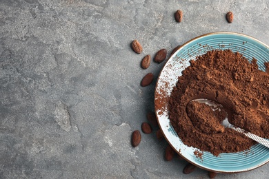 Plate with cocoa powder on grey background, top view