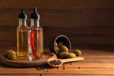 Photo of Different cooking oils and ingredients on wooden table. Space for text