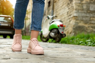 Photo of Woman in stylish sneakers walking on city street, closeup. Space for text