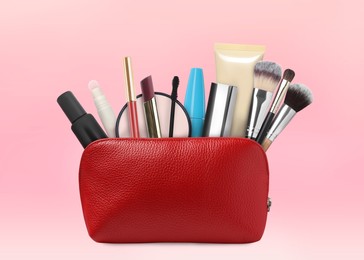 Image of Cosmetic bag filled with makeup products on pink background