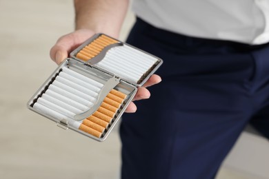 Photo of Man with cigarette case indoors, closeup view