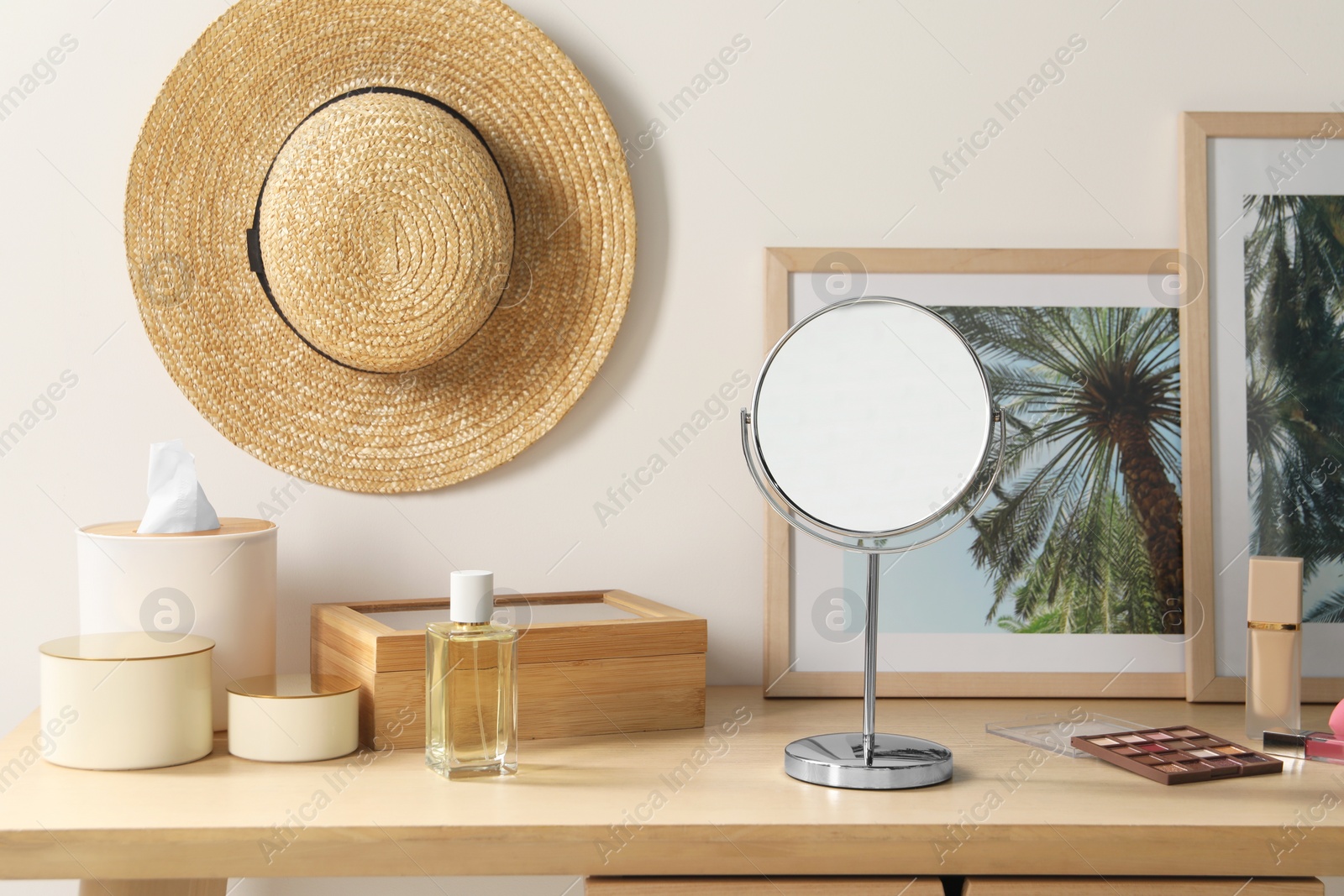 Photo of Mirror, perfume and makeup products on wooden dressing table