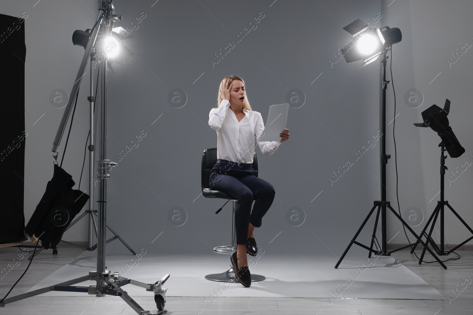 Photo of Casting call. Emotional woman with script performing against grey background in studio