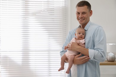 Happy father holding his cute little baby at home, space for text